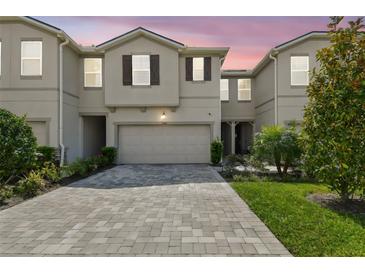 Charming townhome with a well-manicured lawn, brick driveway, attached garage, and neutral exterior paint at 19398 Great Intention Way, Lutz, FL 33558