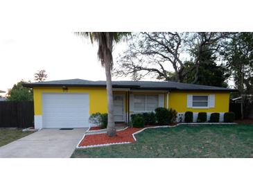 Charming single-story home featuring a bright yellow exterior, well-maintained landscaping, and an attached one-car garage at 2118 Ne Coachman Rd, Clearwater, FL 33765