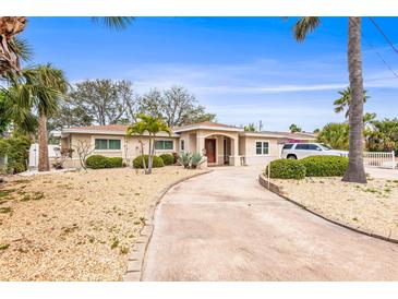 Charming single-story home featuring a well-manicured yard with lush tropical landscaping and a long concrete driveway at 2490 E Vina Del Mar Blvd, St Pete Beach, FL 33706