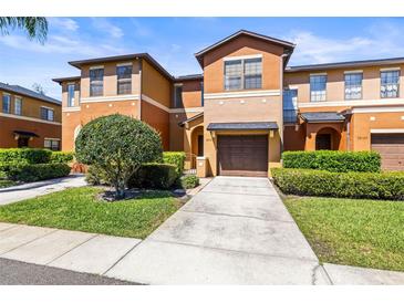 Two-story townhouse features a one car garage and landscaped front yard at 30103 Mossbank Dr, Wesley Chapel, FL 33543