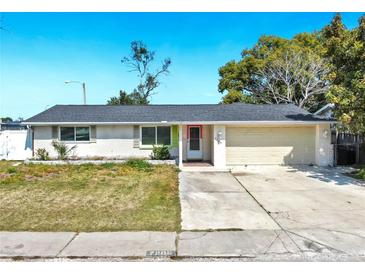 Charming single-story home features a well-manicured lawn, paved driveway, and a welcoming red door at 7205 Mayfield Dr, Port Richey, FL 34668