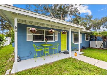 Charming blue home featuring a cozy front porch area with table, chairs, and vibrant hanging flower baskets at 133 15Th Nw St, Largo, FL 33770