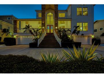 Lovely home at dusk featuring a brick facade, lush landscaping, and a two-car garage in a waterfront community at 2829 Seabreeze S Dr, Gulfport, FL 33707