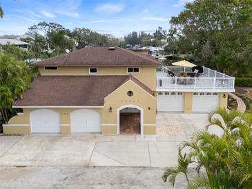 An exterior elevation showcasing a tan home with multiple garage bays and an upper-level balcony at 378 Tennessee Ave, Crystal Beach, FL 34681