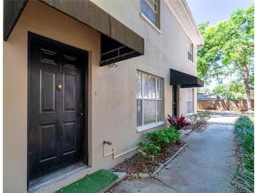 Charming exterior with a classic black door and awning, complemented by neat landscaping at 408 S Arrawana Ave # B4, Tampa, FL 33609