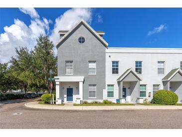 Charming two-story townhome featuring a gray and white exterior with a blue front door and manicured landscaping at 5502 Liberty Plain Cir, Tampa, FL 33611