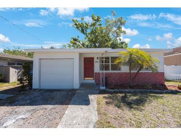 Charming single-story home featuring a red brick facade, palm tree, and a vibrant red front door at 6711 3Rd N St, St Petersburg, FL 33702