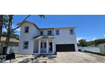 Charming two-story home featuring a modern design, attached garage, and framed by a clear blue sky at 1405 50Th N Ave, St Petersburg, FL 33703