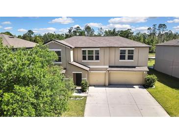 Two-story home featuring a three-car garage, neutral stucco exterior, and well-maintained landscaping at 35965 Saddle Palm Way, Zephyrhills, FL 33541