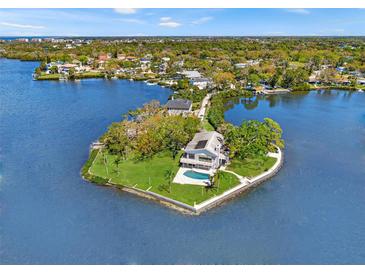 Stunning aerial view of waterfront home with lush landscaping, private pool, and dock on a point lot at 7049 Peninsular Dr, New Port Richey, FL 34652