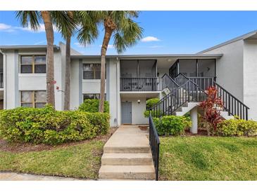 Charming condo featuring a landscaped yard, screened porch, and stairs to the entryway at 1998 Blue Hawk Ct # 1613, Clearwater, FL 33762