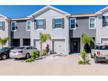 Well-maintained townhomes featuring attached garages, manicured landscaping, and neutral two-tone paint at 34355 Sorrel Mint Dr, Wesley Chapel, FL 33543