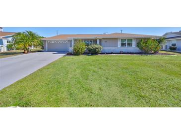 Well-maintained single story home with a green lawn and a two car garage with driveway at 607 Fox Hills Dr, Sun City Center, FL 33573