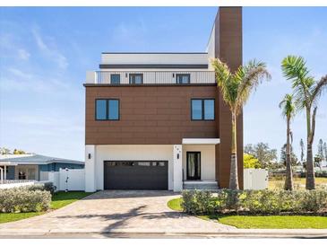 Modern two-story home featuring a balcony, a paved driveway, and lush landscaping at 109 Punta Vista Dr, St Pete Beach, FL 33706