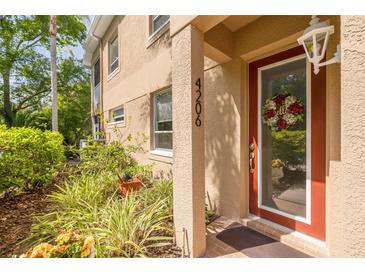 Charming front porch featuring a red door, sidelight and decorative flower wreath at 4206 Preserve Pl, Palm Harbor, FL 34685