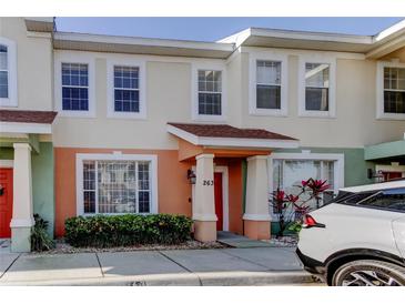 Charming townhome featuring colorful stucco, manicured landscaping, and covered entryway to the vibrant red front door at 263 Alexander Woods Dr, Plant City, FL 33563