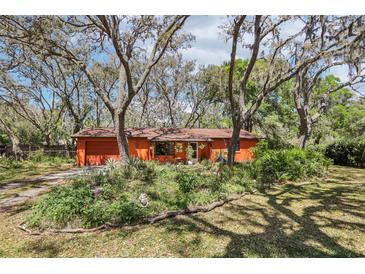 Charming single-story home with lush landscaping, mature trees, and a brick driveway at 33357 Westwood Dr, Ridge Manor, FL 33523