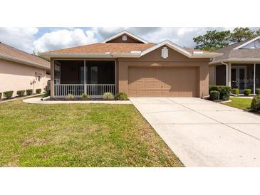 Charming one-story home boasts a well-manicured lawn, a screened-in porch, and a two-car garage at 5664 Legend Hills Ln, Spring Hill, FL 34609