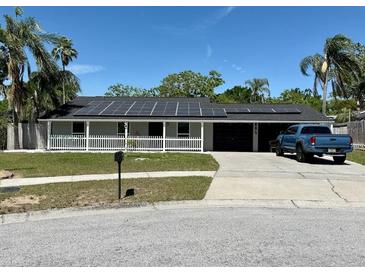 Charming single-story home with a well-manicured lawn, solar panels and a white picket fence enhancing its curb appeal at 804 Valley Hill Ct, Brandon, FL 33510