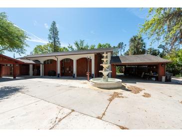 View of garage with arched entries and water fountain in circular driveway at 8820 S Hickory Ln, Riverview, FL 33578