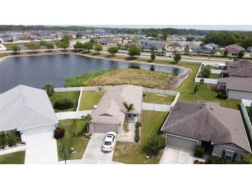 Aerial view of a home with a white fence, waterfront view, and attached two-car garage at 6632 Laxey Ct, Zephyrhills, FL 33541