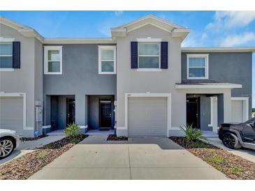 Gray two-story townhome with a one-car garage and a well-kept lawn, providing a welcoming curb appeal at 1967 Hovenweep Rd, Wesley Chapel, FL 33543