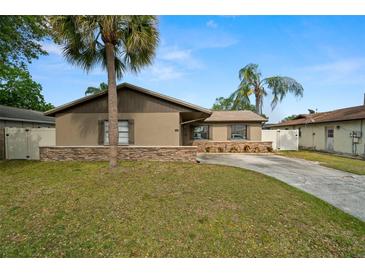 Charming single-story home with stucco exterior, stone accents, driveway, lawn and mature landscaping at 611 Limetree Dr, Oldsmar, FL 34677