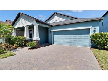 Charming home with blue siding, manicured landscaping and paver driveway leading to a two-car garage at 7215 Wash Island Dr, Sun City Center, FL 33573