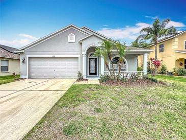 Charming single-Gathering home featuring a two-car garage and well-maintained lawn with mature palm trees at 11414 Weston Course Loop, Riverview, FL 33579