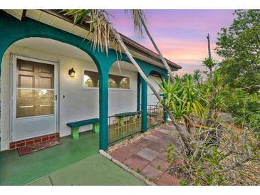 Inviting front porch features arched supports, bench seating and colorful accents at 11705 Ibis Ln, Port Richey, FL 34668