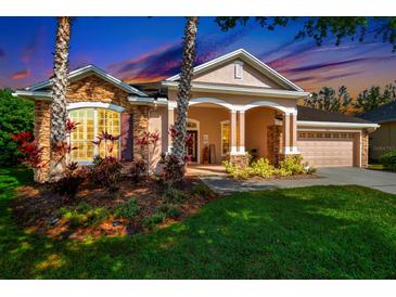 Inviting exterior featuring stone accents, a covered porch with columns, and colorful landscaping at 7051 Derwent Glen Cir, Land O Lakes, FL 34637