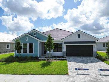 Charming single-story home with a well-manicured lawn, brick driveway, and attached two-car garage at 18051 Foxtail Loop, Venice, FL 34293