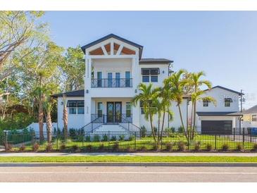 Two-story home boasting white siding, balcony, dark trim, manicured lawn, and complemented by lush palm trees at 526 39Th S Ave, St Petersburg, FL 33705