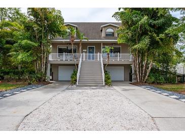 Charming two-story home with a spacious porch, two-car garage, and lush, tropical landscaping at 758 Claudia Ln, Palm Harbor, FL 34683