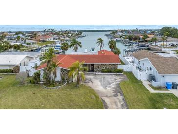 Charming waterfront home with a red tile roof, stone accents, and a spacious driveway at 11755 7Th E St, Treasure Island, FL 33706