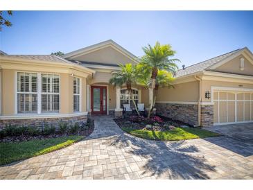 Charming home featuring a red front door, stone accents, lush landscaping, and a paver driveway at 14809 Tudor Chase Dr, Tampa, FL 33626