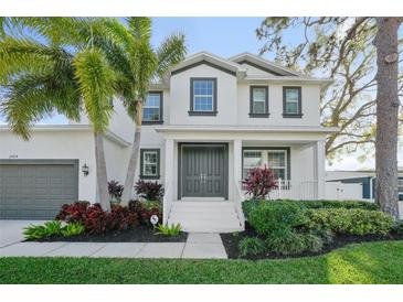Stunning two-story home featuring a welcoming front porch, gray double-door entry, and beautiful tropical landscaping at 2904 W Averill Ave, Tampa, FL 33611