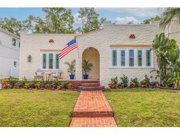 Charming stucco home with a beautiful brick walkway, arched entryway, and an American flag waving proudly at 3512 W Santiago St, Tampa, FL 33629