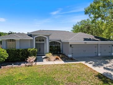Charming single-story home featuring a three-car garage, well-maintained lawn, and lovely landscaping at 4301 Ridgemoor N Dr, Palm Harbor, FL 34685
