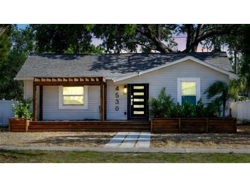 Charming single-story home with a modern black door and inviting wooden porch at 4530 5Th S Ave, St Petersburg, FL 33711