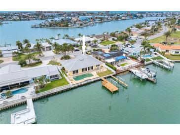 Aerial view of waterfront home with a private pool, dock, and lush landscaping on a sunny day at 512 173Rd E Ave, North Redington Beach, FL 33708