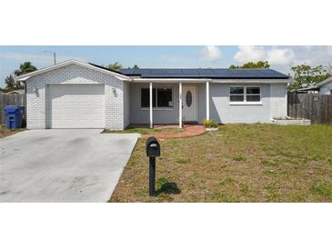 Charming single-story home featuring a brick and stucco facade, solar panels, and a well-manicured lawn at 3207 Coldwell Dr, Holiday, FL 34691