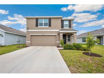 Two-story home with neutral paint, a two-car garage and black shutters at 36727 Spanish Rose Dr, Dade City, FL 33525