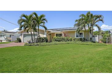 Inviting single-story home with a lush green lawn, tropical palm trees, and a two-car garage at 1361 46Th Ne Ave, St Petersburg, FL 33703