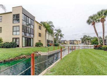 Beautiful condo complex featuring a canal, lush landscaping, and palm trees at 14130 Rosemary Ln # 3312, Largo, FL 33774