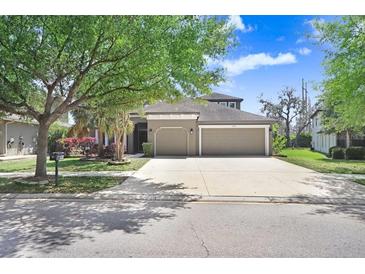 Charming home featuring a well-manicured lawn, mature trees, and a spacious three car garage at 15723 Starling Water Dr, Lithia, FL 33547