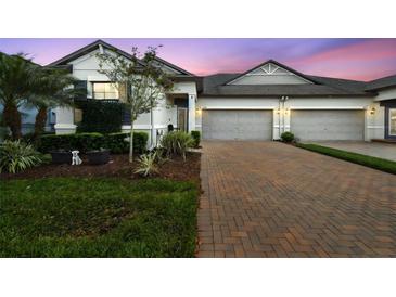 Charming townhome featuring a brick driveway, manicured lawn, and two-car garage at 16822 Balance Cv, Land O Lakes, FL 34638