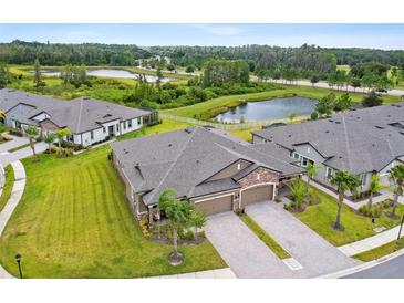 Stunning aerial view of a home featuring lush landscaping, private driveways, and a tranquil lake in the background at 19370 Hawk Valley Dr, Tampa, FL 33647
