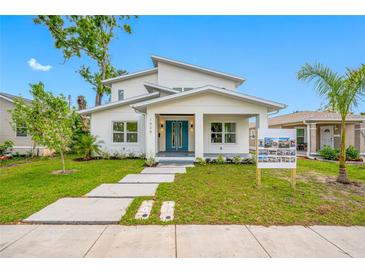 Inviting two-story home featuring a modern design, complemented by a beautifully landscaped front yard and a striking blue double door at 1030 11Th S Ave, St Petersburg, FL 33705