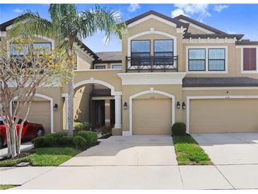 Townhouse exterior with manicured lawn, neutral paint, covered entrance and two-car garage at 11521 Crowned Sparrow Ln, Tampa, FL 33626